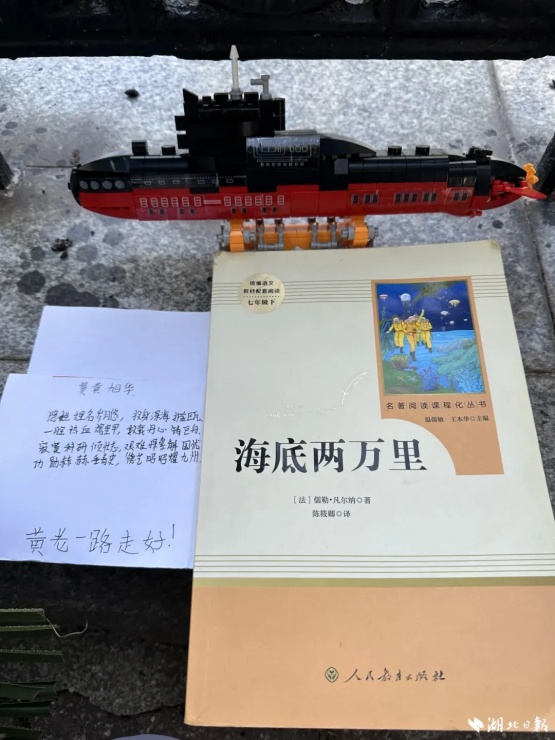 中国船舶集团第七一九研究所，黄旭华院士吊唁仪式入场处，鲜花丛中，有群众特意放上核潜艇和模型和《海底两万里》书籍。.jpg